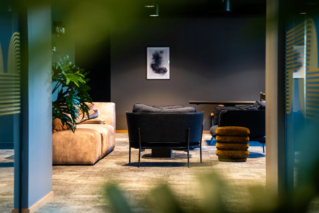 Brett tjänsteutbud. Arkitektbyrå i Stockholm. Mörk och mysig kontorsmiljö med gröna blad i förgrunden